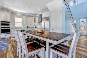 A modern kitchen with white cabinetry, a central island with seating, and a stainless steel refrigerator. - P24 - Fabulous 4 bed, 4 bath home with pool and dock (Key Colony Beach)