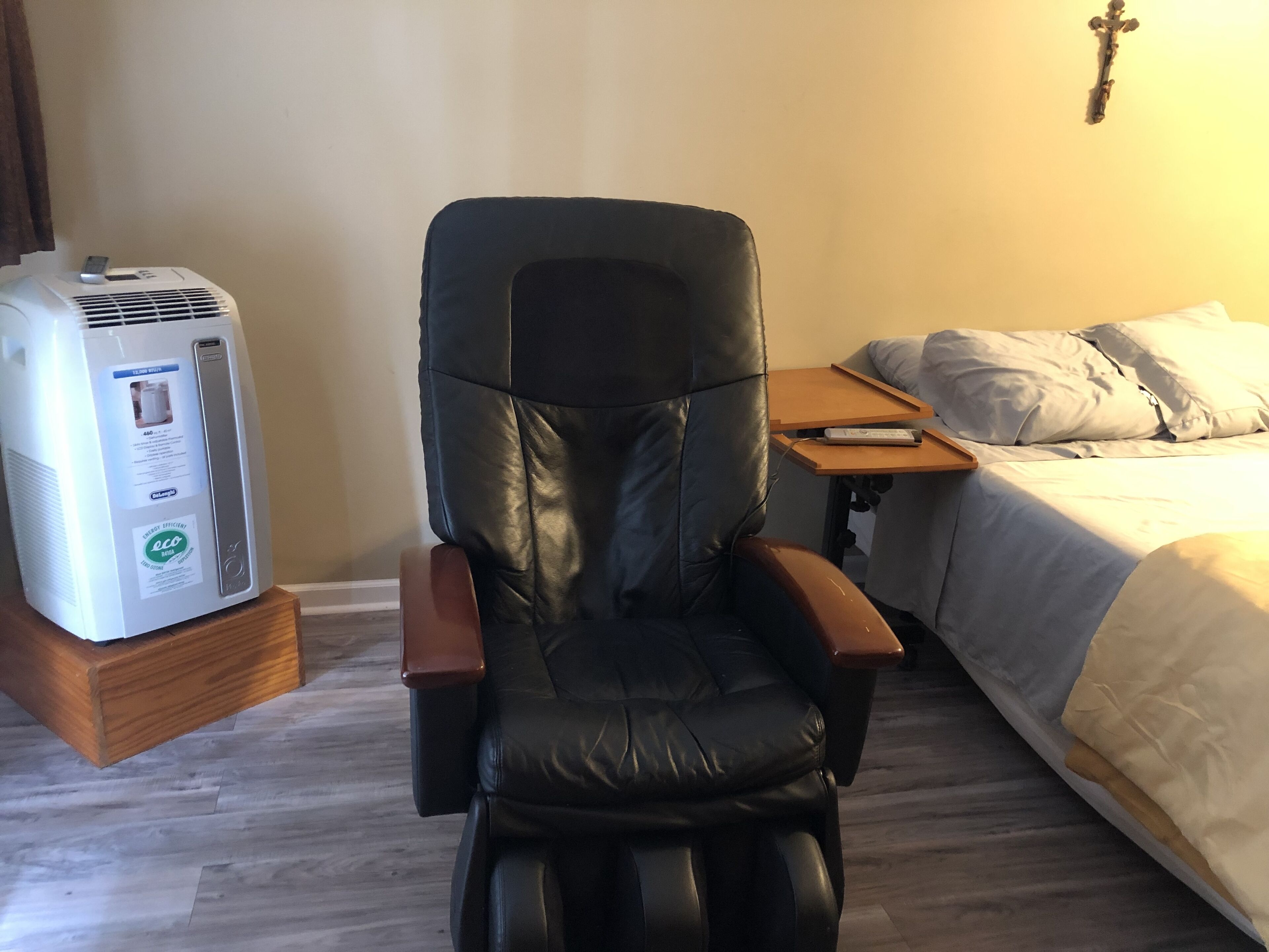 Ein Massagesessel in einem Hotelzimmer, mit einem Bett und einem kleinen Tisch.