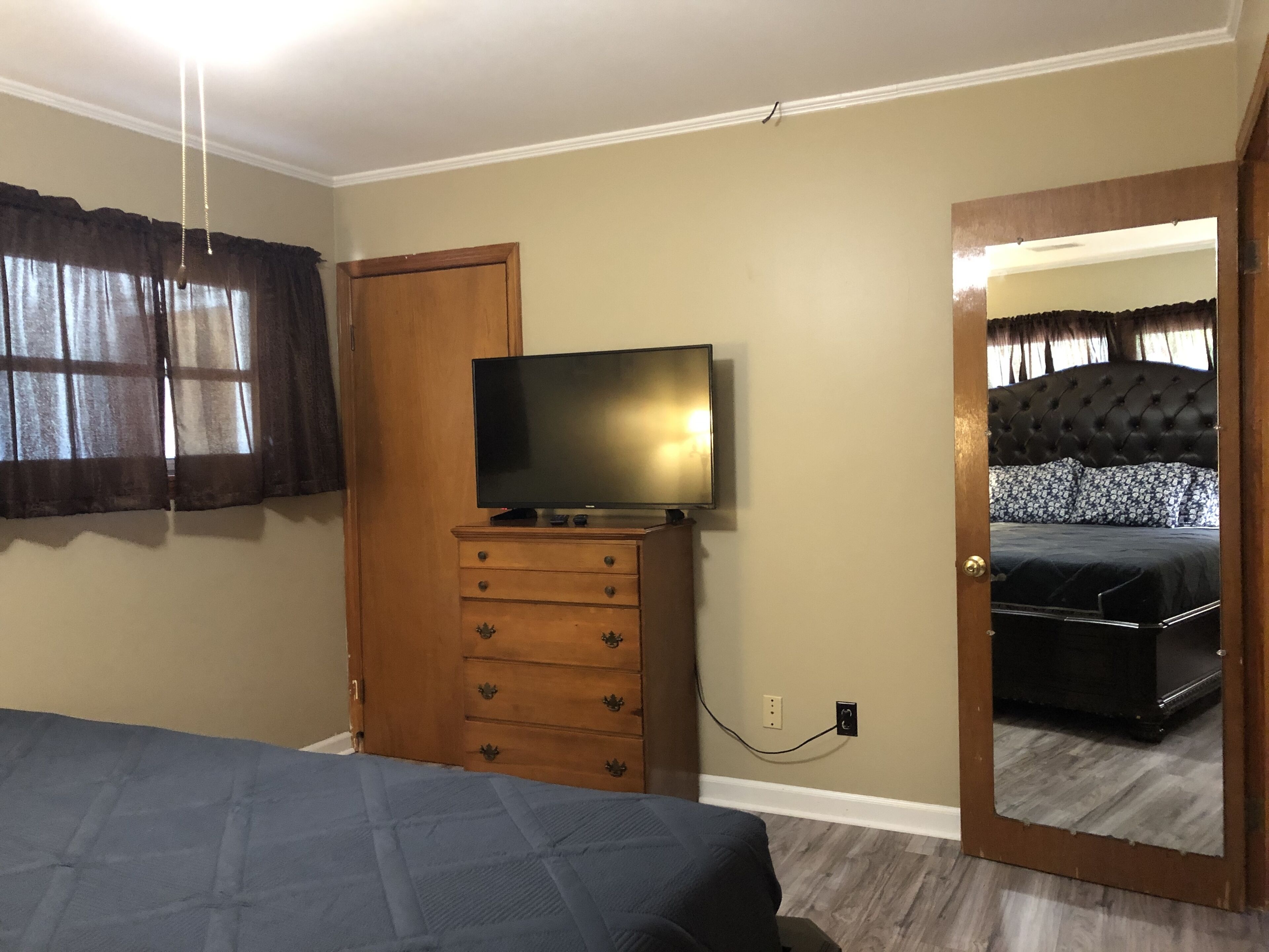 Un dormitorio con cama, cómoda, televisor y espejo.