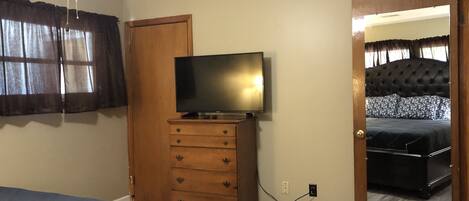 Un dormitorio con cama, cómoda, televisor y espejo.