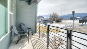 A balcony with two striped chairs and a bench, overlooking a parking lot with snow and mountains in the background. - Montana Modern Condo close to Shopping and the Yellowstone River. (Livingston)