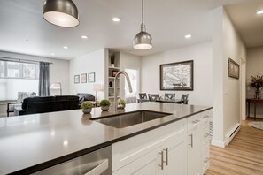 A modern kitchen with a large island, white cabinetry, and pendant lighting.
