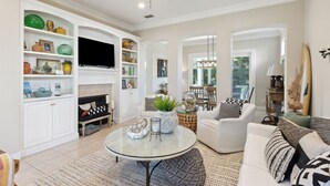Un salon spacieux avec une cheminée, des meubles blancs et un téléviseur.