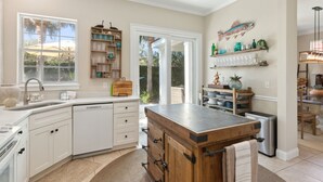 Une cuisine moderne avec des meubles blancs, un îlot central et une grande fenêtre.