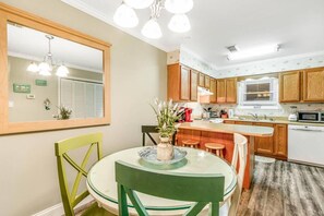 Une cuisine moderne avec des meubles en bois, une table à manger avec des chaises et un grand miroir au-dessus de la table.
