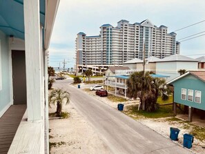 Une route côtière bordée de propriétés en bord de mer, un hôtel à plusieurs étages en arrière-plan et une petite maison avec un toit bleu.