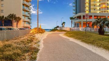 A road leading to a hotel with a 'No Parking' sign, a beach in the background, and a clear sky.