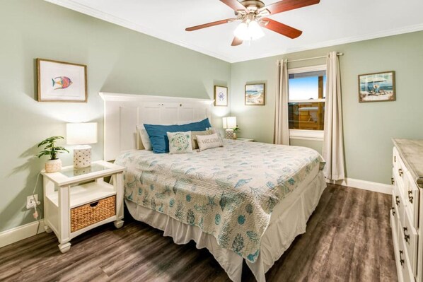 Une chambre à coucher avec un lit, une table de chevet, une lampe et un ventilateur de plafond.