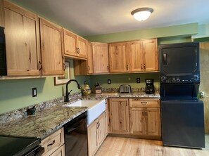Kitchen area with a refrigerator, stove, sink, toaster, and coffee maker.