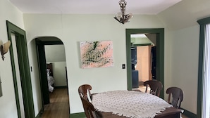 A dining room with a wooden table and chairs, a ceiling light, and a painting on the wall.