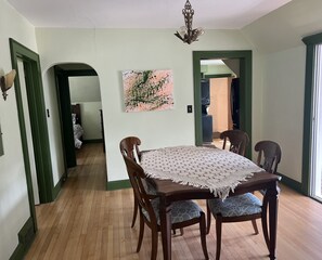 Enjoy meals in this dining area with a table for four, surrounded by matching chairs and a beautiful painting.