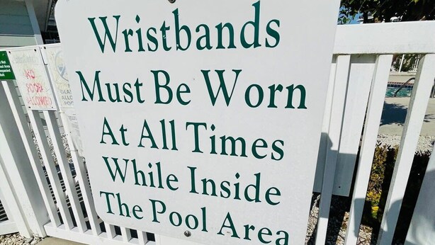 En skylt med texten: ”Armband måste bäras hela tiden när man befinner sig i poolområdet.”
