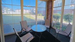 Ett uterum med ett glasbord och stolar, en tegelbeklädd accentvägg och utsikt över ett bostadsområde.