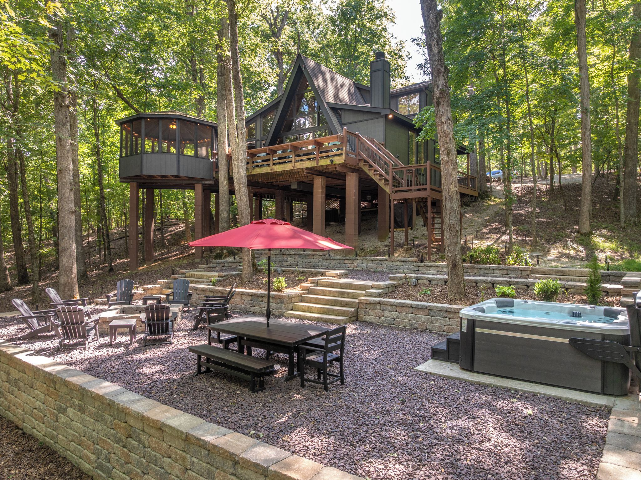 A cabin with a deck, outdoor seating, and a hot tub.
