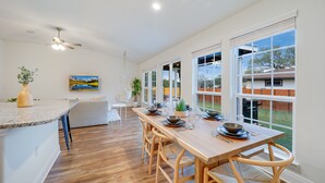 A modern kitchen with a wooden dining table, chairs, and a built-in island. - Hill Country Retreat | Hot Tub | Fire Pit (Lago Vista)