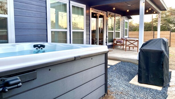 A modern house with a covered patio, a hot tub, and a barbecue grill. - Hill Country Retreat | Hot Tub | Fire Pit (Lago Vista)