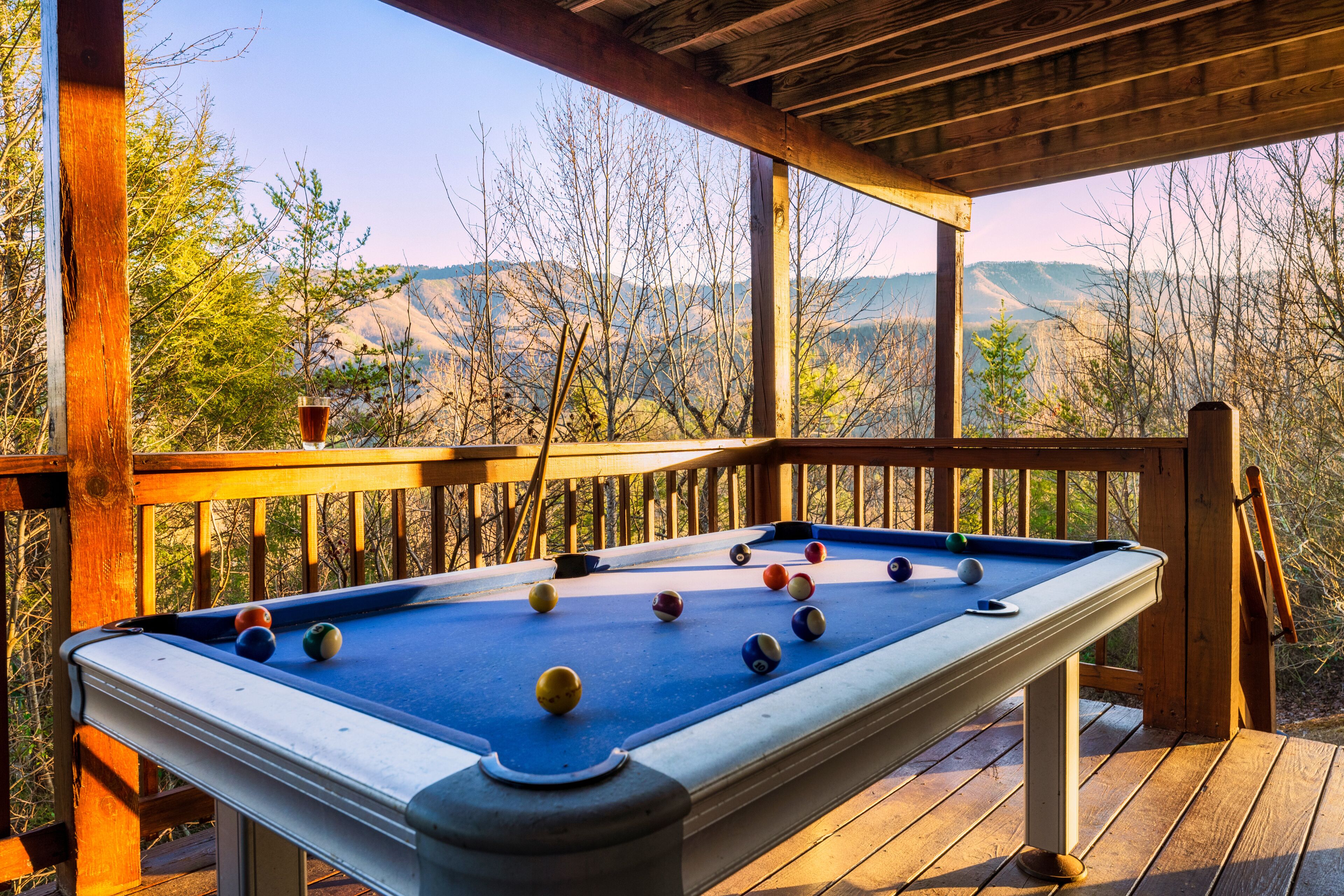 A pool table on a wooden deck with a view of mountains.