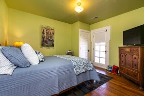 Un dormitorio con cama, cómoda, televisor y puerta.