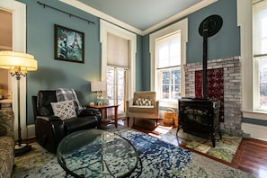 Un salón acogedor con chimenea, un sofá de cuero, una mesa de centro de cristal y una alfombra azul estampada.
