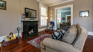 Ein Wohnzimmer mit Kamin, einer Couch, einem Teppich und einem Esstisch.