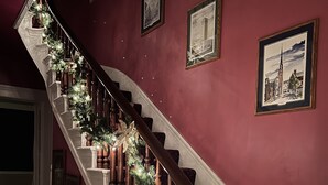 Eine Treppe mit Holzbalkonen, weißen Geländern und einer Girlande mit Lichtern und einer großen goldenen Schleife.