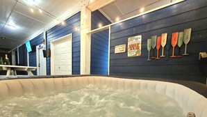 Un jacuzzi con un muelle de madera, una pared azul con revestimiento de madera y un letrero que dice 'Bienvenido al Jacuzzi'.
