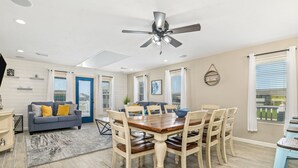 Un salón amplio con comedor, ventilador de techo y vistas al exterior.