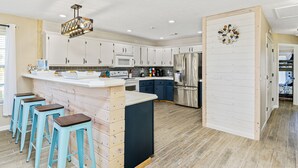 Una cocina moderna con armarios blancos, un refrigerador de acero inoxidable y una isla central con taburetes.
