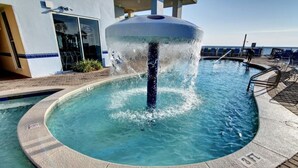 A circular pool with a water fountain in the center, surrounded by a deck with chairs. - Million-Dollar Gulf Views • Majestic Beach Resort 504 Tower 1• Beachfront • Pool (Panama City Beach)