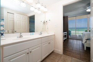 A bathroom with a large mirror, two sinks, and a ceiling fan.