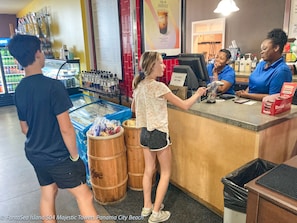 A counter with a menu, a beverage dispenser, and a trash bin.