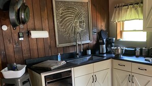 A kitchen with wooden walls, a black countertop, white cabinets, a hanging pot rack, and a window with curtains. - Near SkiSawmill 5 mi ETAR,STAR Archery, PAWA events. On the stream!   (Waterville)