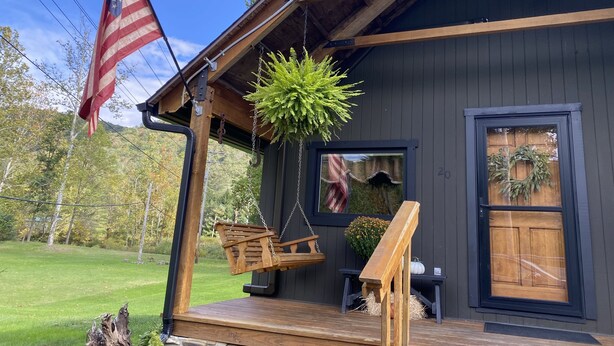 A wooden cabin with a porch, a hanging fern, a wooden swing, and an American flag. - Near SkiSawmill 5 mi ETAR,STAR Archery, PAWA events. On the stream!   (Waterville)