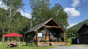 A rustic cabin with a porch, a picnic table, and a red canopy. - Near SkiSawmill 5 mi ETAR,STAR Archery, PAWA events. On the stream!   (Waterville)