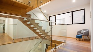 A modern interior with a glass and wooden staircase, a wooden floor, and a grey armchair with a blue ottoman. - Stunning Waterfront Home in Surfers Paradise.
Heated Pool and Pet Friendly (Surfers Paradise)