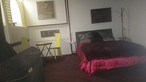 A bedroom with a large bed, a small table, a chair, and a coat rack. - Rainforest setting with sunset views (Tamborine mountain)