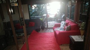 A living room with a red carpet, a red sofa, and a small table with a vase. - Rainforest setting with sunset views (Tamborine mountain)