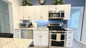 A modern kitchen with white cabinets, stainless steel appliances, and a granite countertop. - Your Family Friendly Home with Large Backyard & Onsite Parking (New Rochelle)