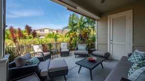 Un patio cubierto con mobiliario de mimbre, una mesa de centro y vistas a un barrio residencial.