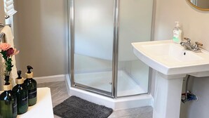 Un baño con cabina de ducha de vidrio, un lavamanos blanco y un espejo.