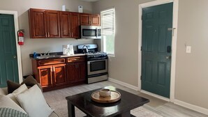 Cocina compacta con armarios de madera, microondas, estufa y cafetera.