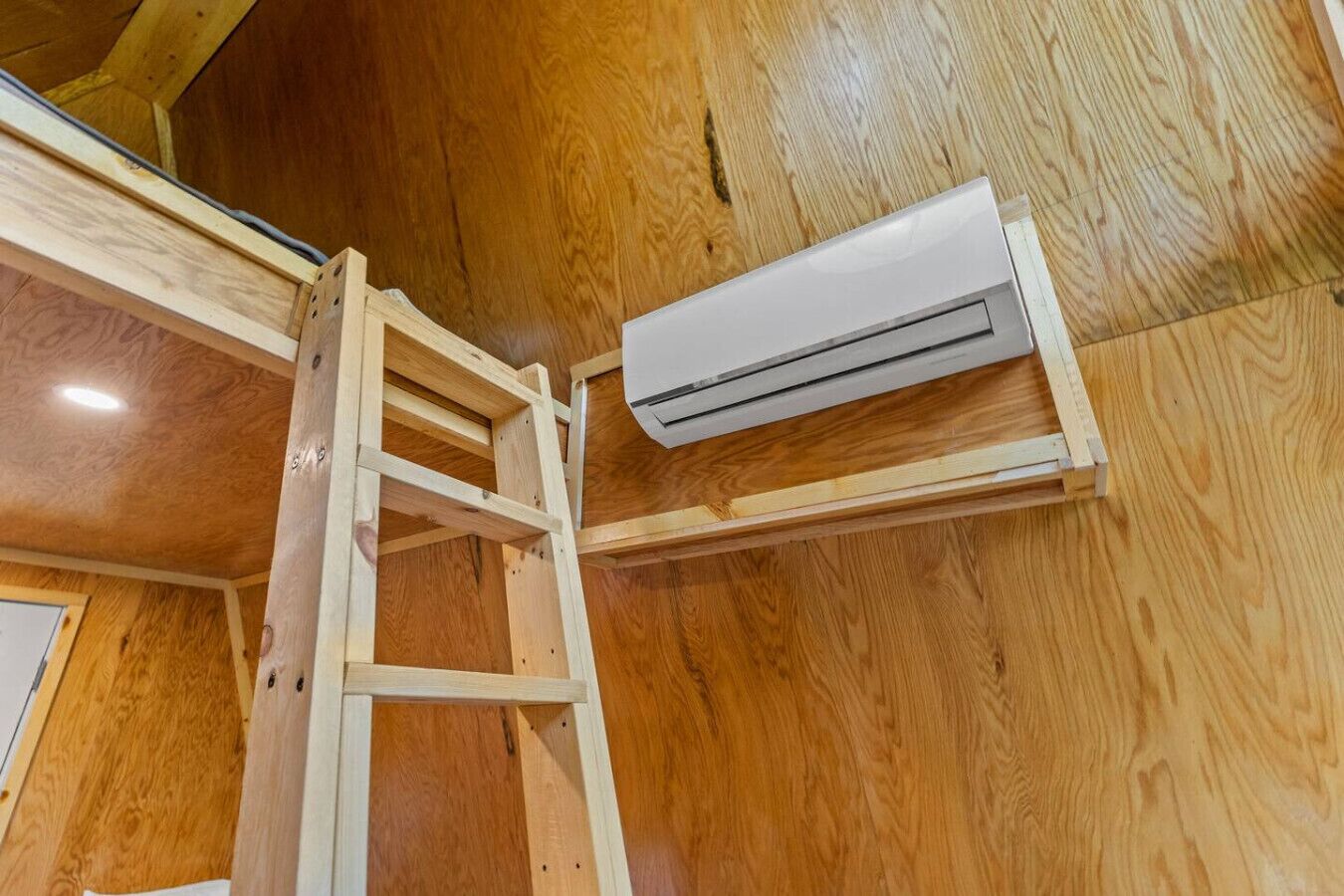 A wooden interior with a ladder and an air conditioning unit mounted on the wall.
