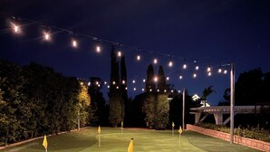 Een verlichte kunstgras golfbaan 's nachts, met lichtjes erboven.