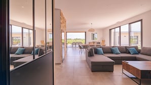 A spacious living area with a large sectional sofa, a coffee table, and a dining area with a table and chairs. - Villa with exceptional 4-star certified viewSPA and heated infinity pool (Servian)