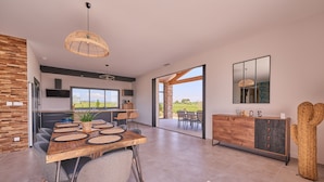 A modern kitchen with a dining area, large windows, and a view of the outdoors. - Villa with exceptional 4-star certified viewSPA and heated infinity pool (Servian)