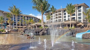 Un resort con fontana, palme e un edificio con numerosi balconi.