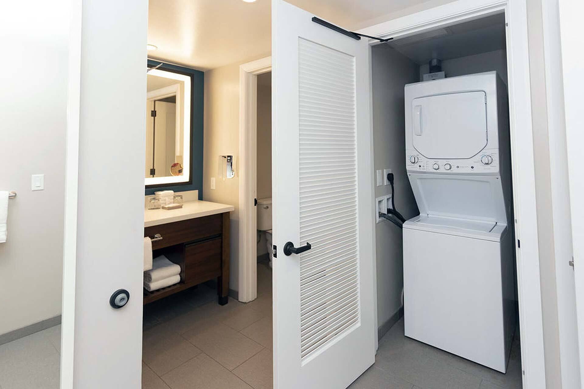 Une chambre d’hôtel avec une salle de bain, un lave-linge blanc et une porte dotée d’une poignée.