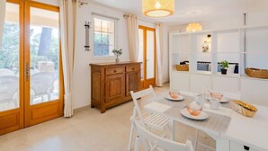 A bright, modern kitchen with white cabinetry, a wooden dining table, and a hanging light fixture. - Marysol by Interhome (Les Issambres)