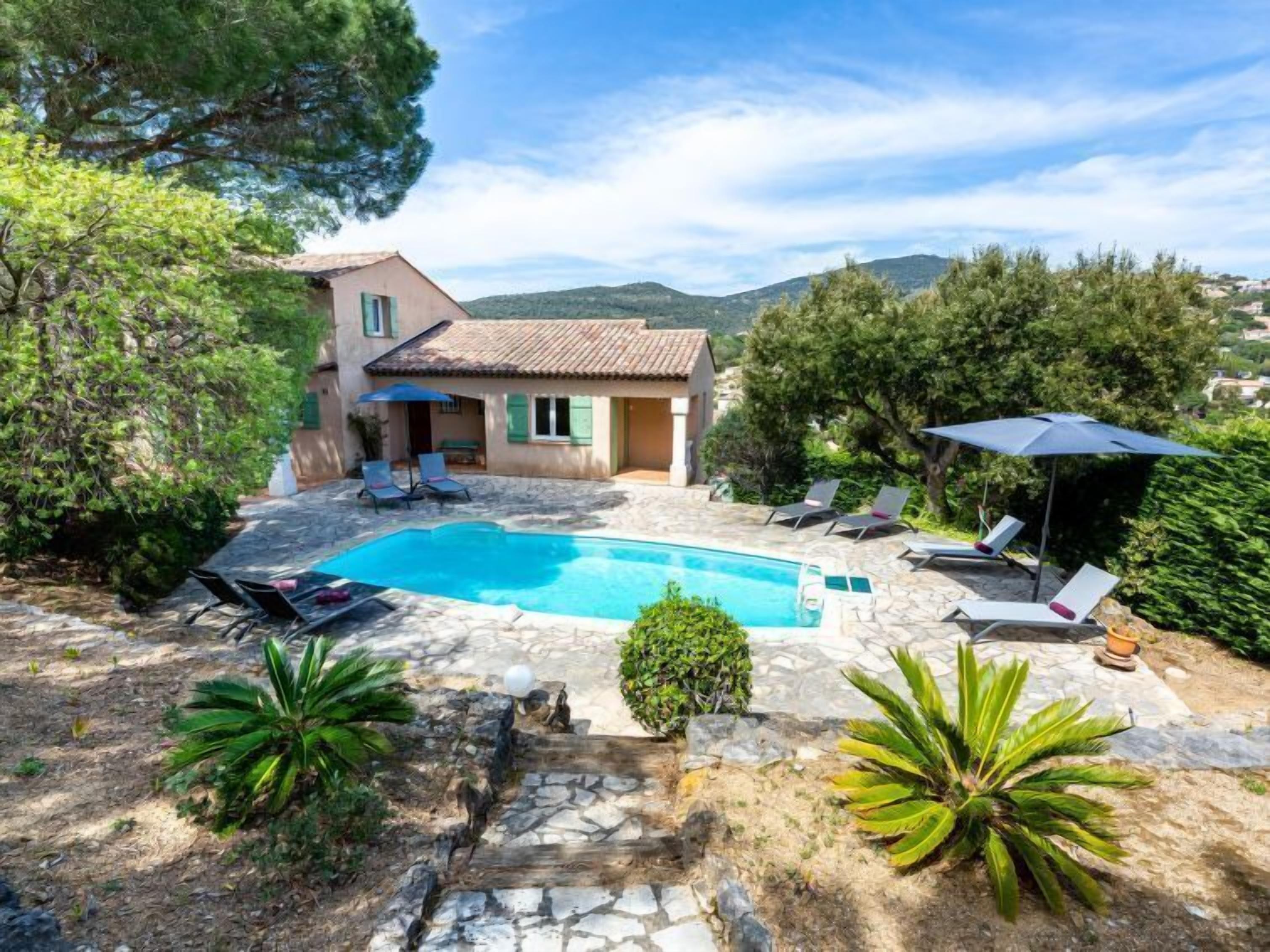 Una villa con piscina, mobiliario de exterior y vistas a las colinas.