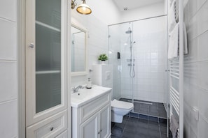 Ein modernes Badezimmer mit Duschkabine aus Glas, weißem Waschtisch und Toilette.